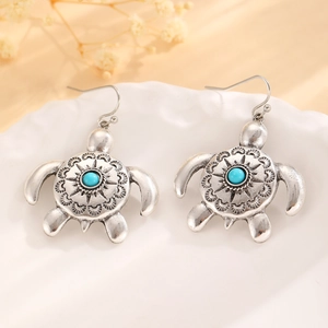 Detail of vintage silver turtle earrings with blue turquoise stones on a ceramic tray