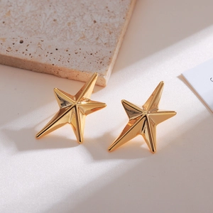Detailed view of glossy gold star earrings on premium white silk with elegant stone backdrop