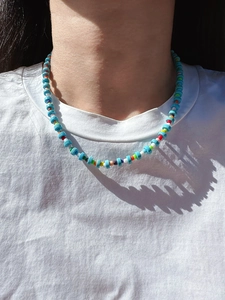 Detail shot of a bohemian turquoise bead necklace worn by a model in soft sunlight