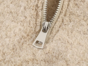 Détail de fermeture éclair en métal argenté et tissu polaire sherpa sur le pull doux