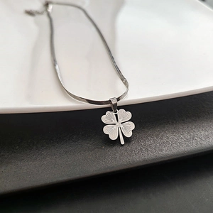 Silver titanium steel four-leaf clover pendant necklace with snake chain on a dish