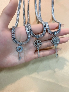 Detailed close-up of three sparkling silver-toned key necklaces with embedded rhinestones