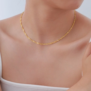Detail shot of a delicate golden water wave chain anklet with polished metallic finish