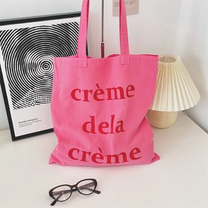 Detail der rosa Canvas-Tasche mit rotem Crème de la Crème Aufdruck auf weißem Dekor