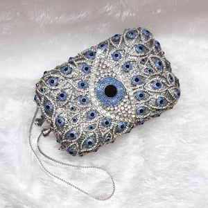 Macro shot of silver and blue crystal evil eye pattern on luxury clutch bag