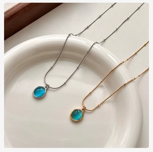 Detailed view of blue cat-eye stone pendants on gold and silver beaded necklaces