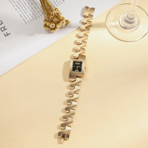 Macro detail of a gold chain watch with a rectangular black dial and Z-shaped metal link strap