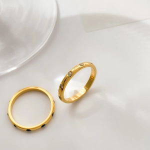 Detail of two gold rings featuring inlaid sparkling white and black zircon stones