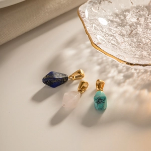 Detailed shot of geometric rose quartz, lapis lazuli and turquoise pendants with gold clasps