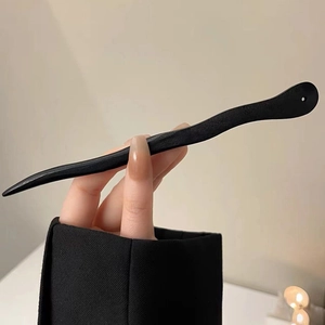 Détail d'un pic à cheveux minimaliste en bois d'ébène ondulé pour chignons élégants