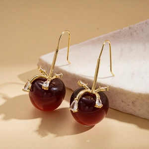 Gros plan de boucles d'oreilles cerises dorées avec pierres résines rouges et zircon