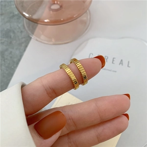 Close-up of dual gold rings with textured grooves on model hand for minimal styling