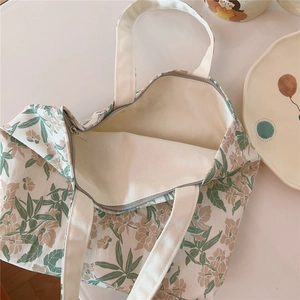 Detail of floral cotton tote bag featuring leaf patterns and a smooth zipper closure