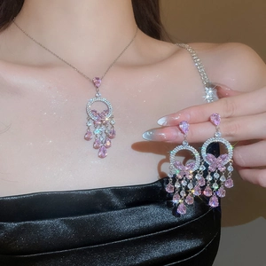 Detail of pink zircon butterfly tassel necklace and earrings set worn with black dress