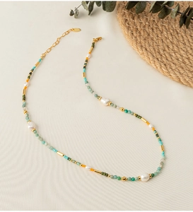 Detail of bohemian beaded necklace with natural stones, pearls, and gold extender chain