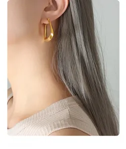 Detail of minimalist 18k gold plated U-shaped hoop earrings on female model