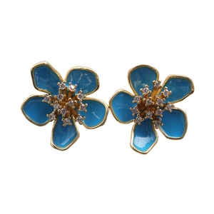 Detailed view of blue enamel flower stud earrings with gold plating and zircon centers