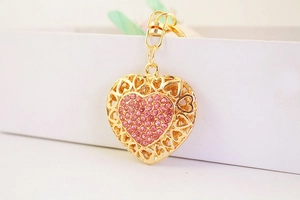 Detail of a golden heart keychain featuring pink rhinestones and a secure spring clasp