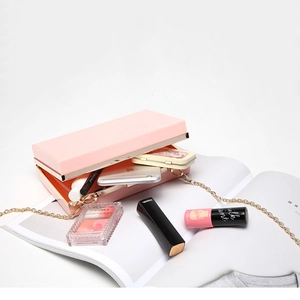 Pink acrylic box clutch with gold metal trim and chain strap on a white background