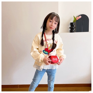 Detail of a young girl wearing a cream sweatshirt with a cute red bow crossbody bag