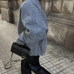 Detail of grey oversized wool jacket paired with black leather pants and handbag