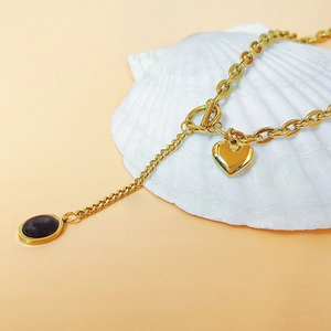 Golden heart necklace with OT buckle, brown gemstone pendant on a white shell background