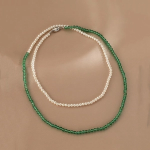 Close-up of pearl and green agate necklace on champagne gold luxury satin fabric