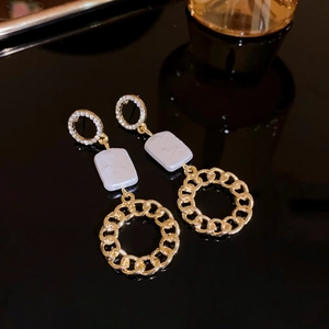 Detail view of gold star earrings with pearl charms and rhinestone hoops on black surface