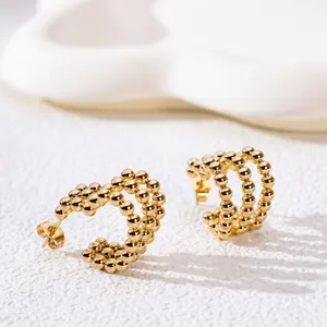 Luxury gold beaded C-shape hoop earrings with a triple-row ball design on stone surface