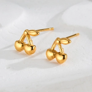 Minimalist gold cherry stud earrings in stainless steel on white stone background