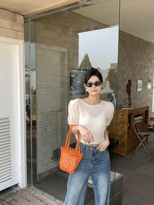 Detail showing the wavy wrinkled texture of the creamy white short-sleeve knit top