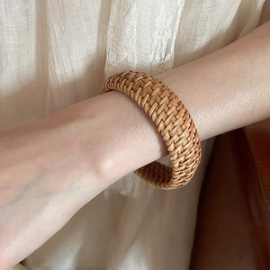Gros plan d'un bracelet large en rotin tressé à la main au style bohème chic