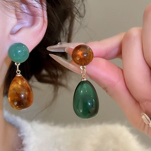 Detail of green and amber resin water drop earrings shown on a model for a vintage look