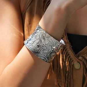 Detailed macro view of silver open cuff bracelet with vintage floral paisley engravings