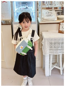Detail view of child's green crossbody bag with daisy floral embroidery on young girl