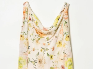 Detail von geblümtem Stoff mit gelben und orangen Blumen an einem drapierten Sommerkleid