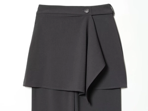Detail of dark grey layered trousers with asymmetrical wrap design and black button accent