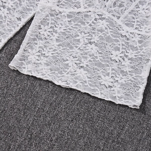 Detailed close-up of intricate white floral lace fabric and mesh texture on a V-neck top