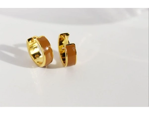 Close-up of golden hoop earrings featuring brown enamel inlay and clasp closure
