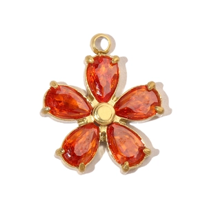 Close-up of golden five-petal flower pendant with orange gemstones and metal center
