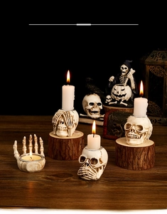 Detailed view of Halloween skull candle holders with warm candle flames on wooden surface
