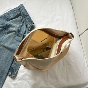 Off-white canvas tote bag with brown leather trim and spacious interior storage