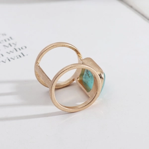 Detailed view of a gold double-band ring featuring a square turquoise gemstone centerpiece