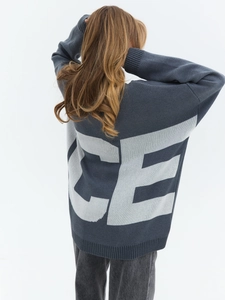 Close-up of the grey oversized knitted sweater featuring white jacquard CE lettering on back