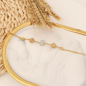 Detail of gold snake chain bracelet with blue enamel heart pendant and beads on a tray
