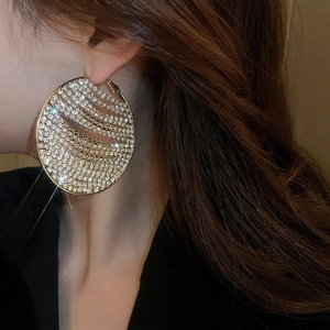 Close-up of oversized gold hoop earrings with sparkling rhinestones on female model