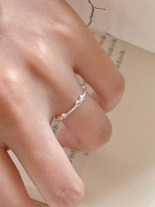 Close-up of 925 sterling silver bow pattern open ring worn on finger with soft lighting