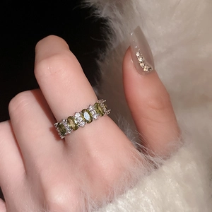 Detail of vintage silver ring featuring olive green gem and white diamonds on hand