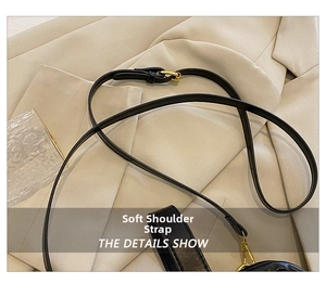 Detail of soft black leather shoulder strap with gold metal buckle on beige fabric
