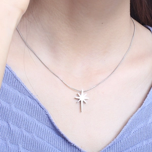 Detailed view of a silver octagonal star pendant on a snake chain worn by a model
